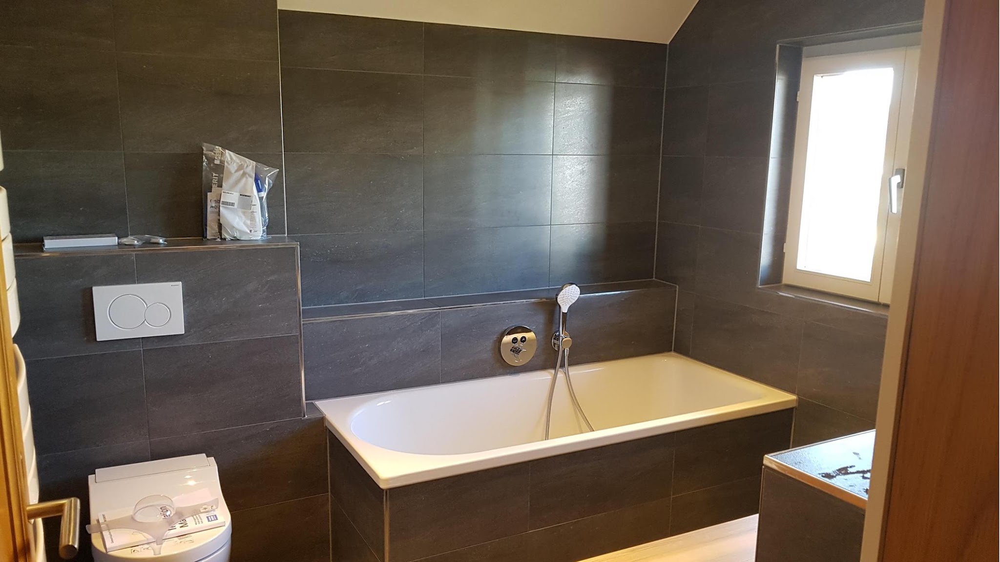 Fertig saniertes Bad mit dunklem Feinsteinzeug und freistehender Badewanne