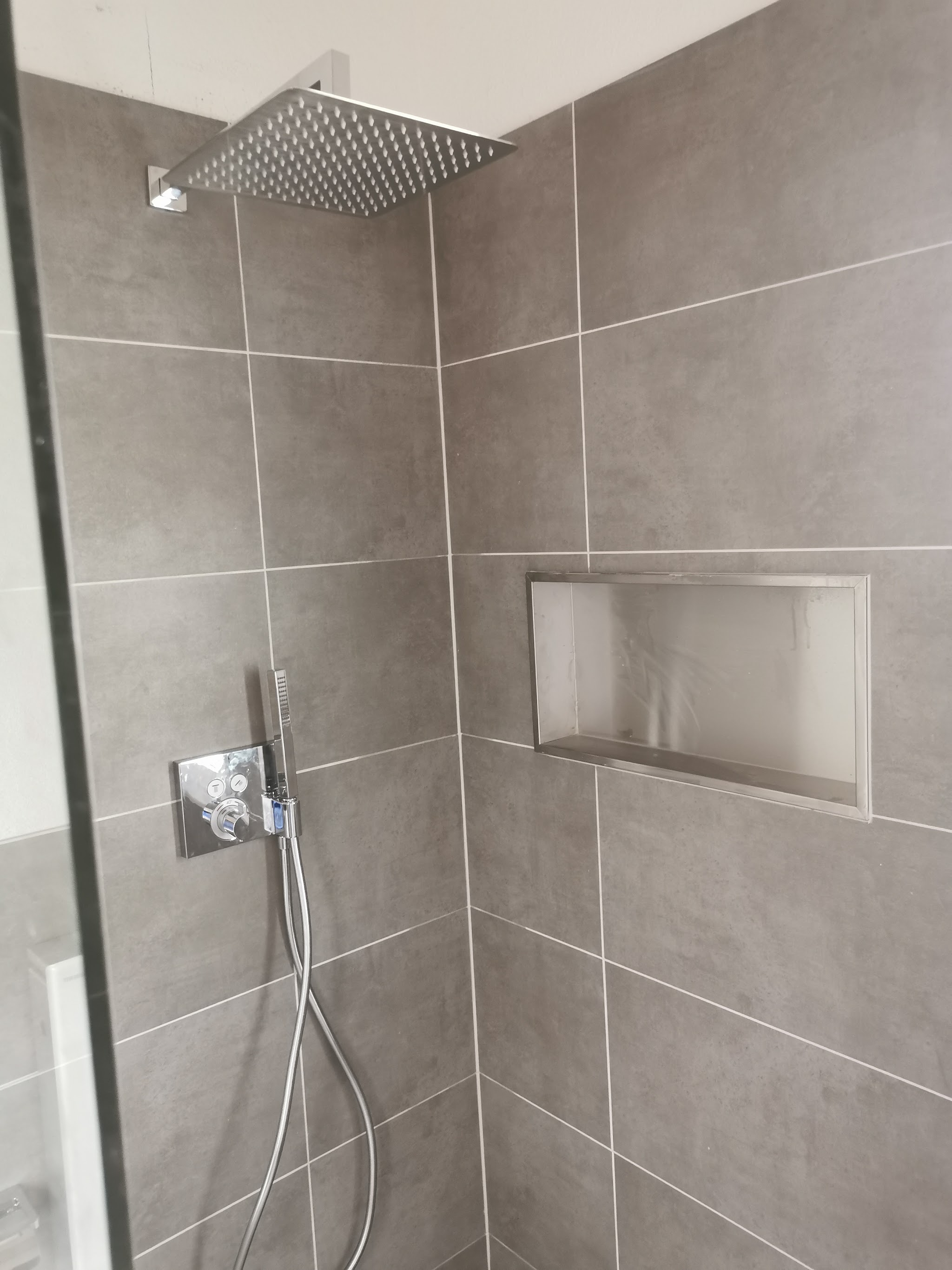 Detailaufnahme von Kopfbrause und Ablagenische in Feinsteinzeug