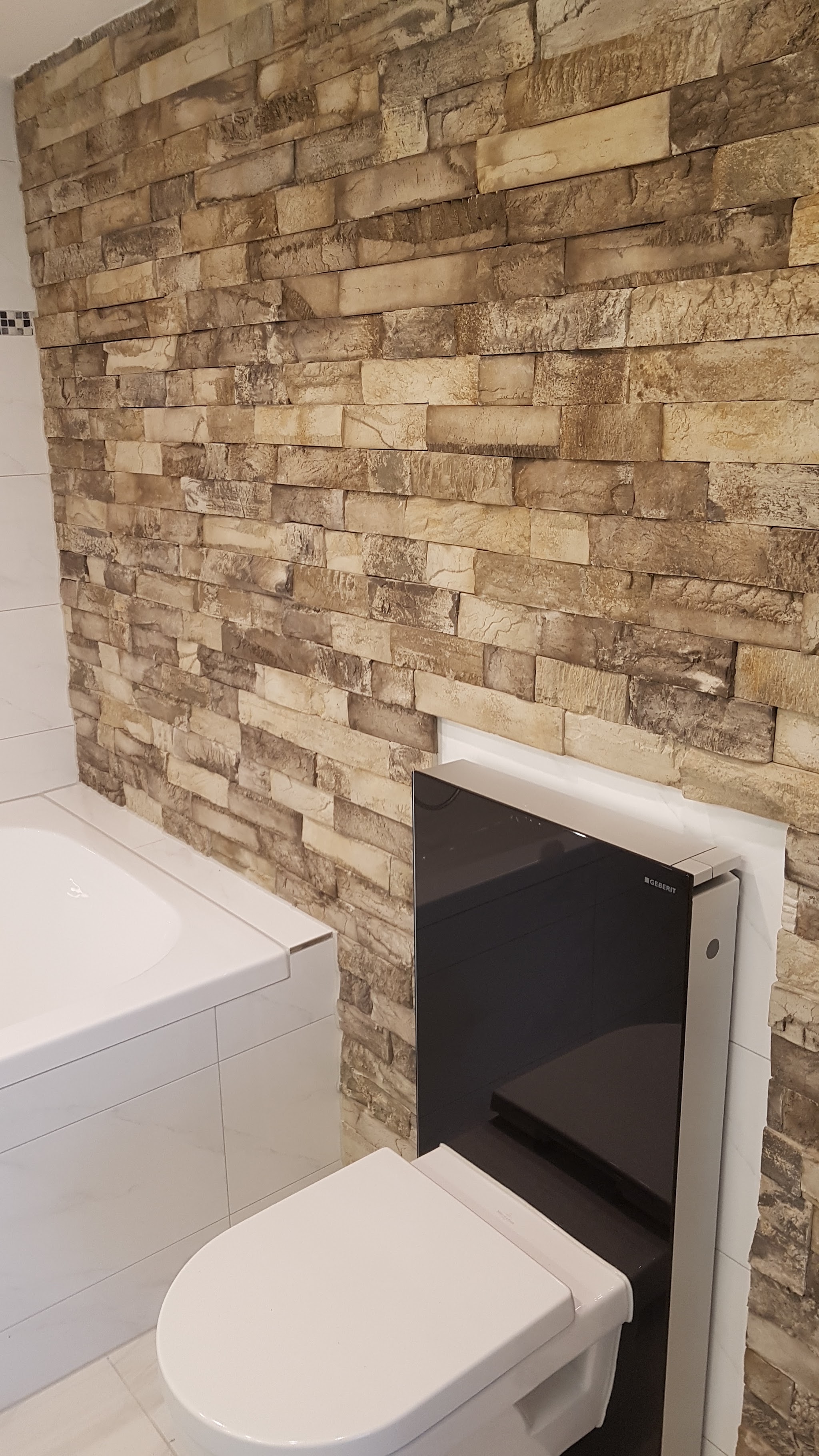 Handwerklich verlegte Natursteinoptik-Wand mit Geberit Spülkasten