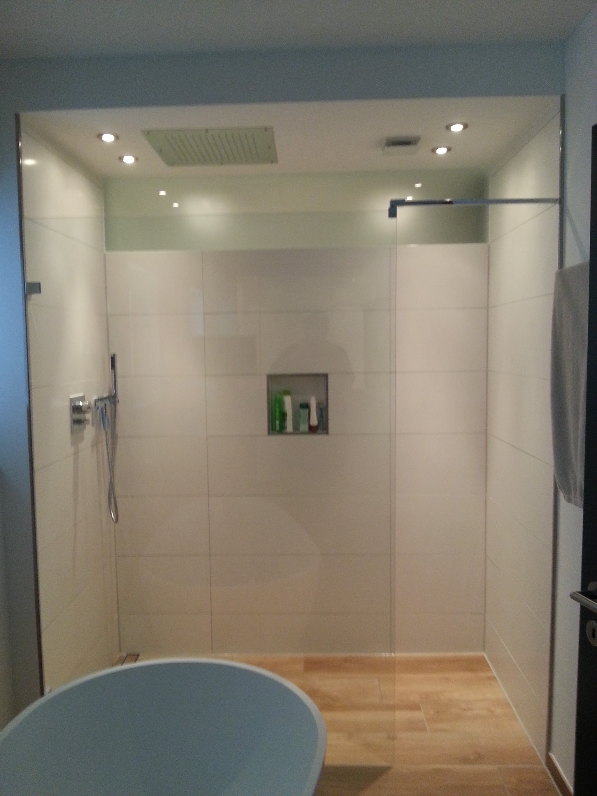 Grosszügige Dusche mit Kopfbrause und Holzoptik-Boden